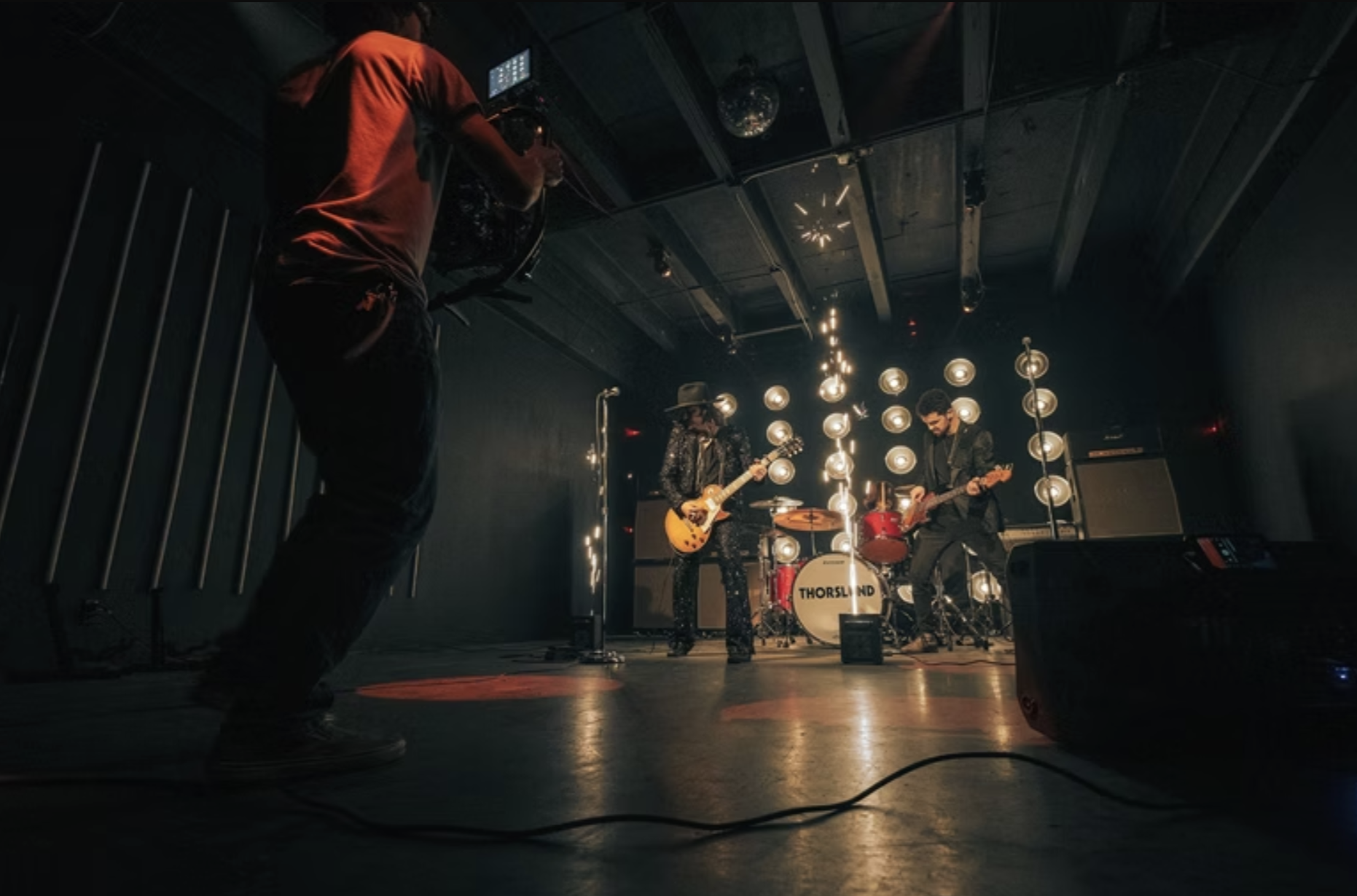 A videographer filming a live band on stage.
